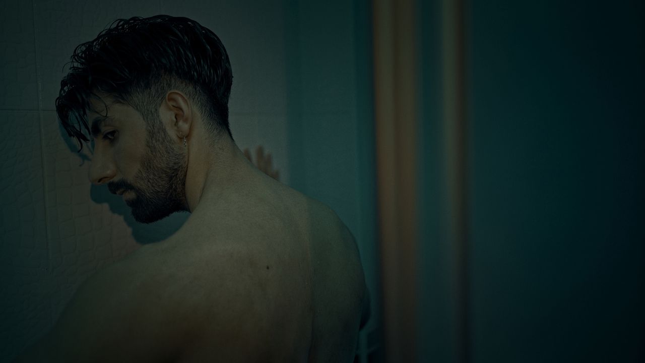 Thoughtful portrait of a man in a dimly lit room, capturing his side profile and introspective mood.